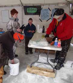 Tom Cary (red coat) measures fish during the Wolford Ice Fishing Tournament.