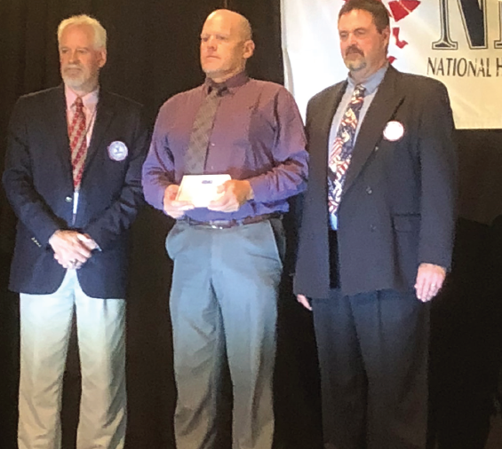 Coach Chris Brown (center) accepts his award as a finalist for Head Coach of the Year. Brown is currently the winningest coach in the state and the Mustang 8-man team were second in the state last year.