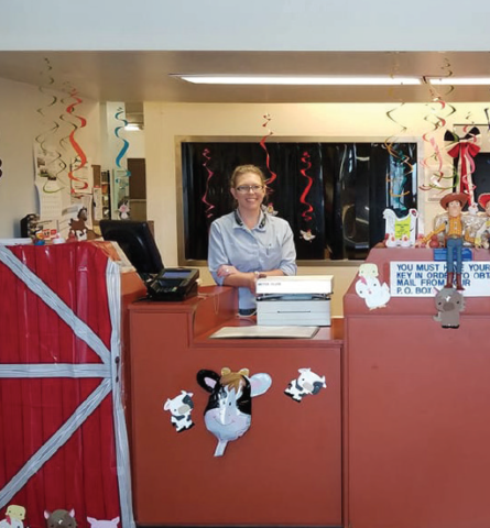photo by Cindy Multerer Jennyfer Jones stands behind the festive barn theme at the Kremmling post office. Postmaster Christa Kopp has been doing theme related decorations for holidays and heralded the annual fair event. The Middle Park Fair & Rodeo will begin Friday, August 3 and continue through August 12.