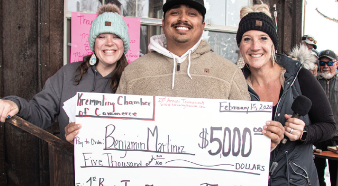 photo by Kim Cameron | Ben Martinez won over $6000 at the ice hole fishing tournament. He was awarded his check for the tagged fish from Chamber directors - Brittany Vanderlinden and Tara Sharp.