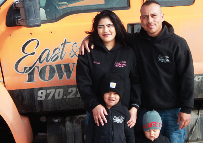 Owners of East West Towing, Mike and Leslie Osorio, stand in front of their first tow truck with sons Zani and Khallen. The family's business has expanded to include 2 flatbeds, a wrecker, and a service truck.