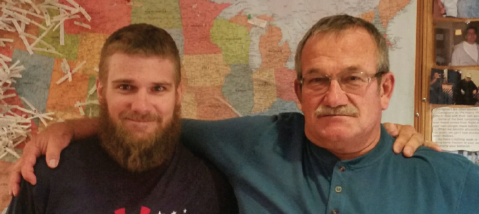 Cole and Keith Wilsey stand in front of a map of transplant donors from across the Western US. Father and son were at a transplant lodge in Oregon, where Cole would donate a kidney to his father.