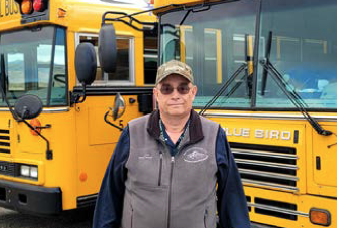 James Gregory stands in front of part of his fleet of buses, including the new elecrical bus. He and his wife, Kathryn and son, Eric, will all be moving to Missouri. Kathryn works at Kum and Go. The whole family will be missed.