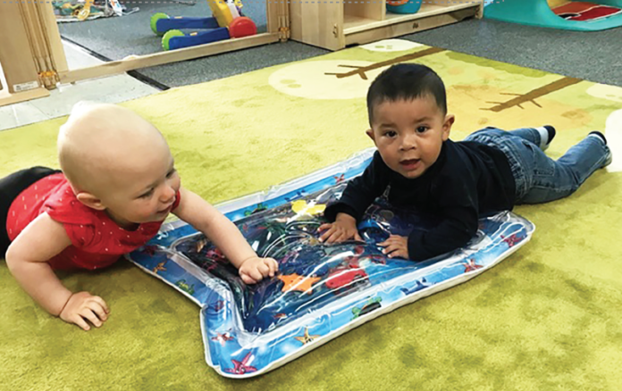 photo courtesy of West Grand Early Childhood Center | Bradley Rodriguez and Amelia Winter learn the basics of sharing and playing together in the infant room at the West Grand Early Childhood Center.